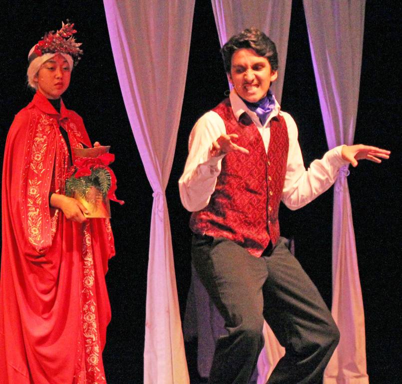 Scrooges nephew, Fred, played by senior Kanoa Yap, imitates his uncle in a game of Yes or No in the drama departments production of A Christmas Carol. The Ghost of Christmas Present, sophomore Kaili Mossman, is an eerie presence in the background.