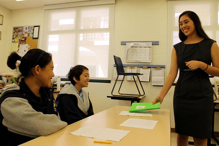 Malie Cathcart hands out a folder to juniors Madison Williams and Mikayla Lau, who watched her presentation. Hōike Nui presentations were held Nov. 12, at the high school campus.
