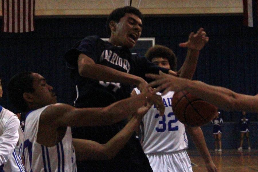 Dayson Damuni, junior, fights for the ball with multiple Sabers on him, Saturday, January 25, at the Maui High School Gymnatorium. The Warriors won, their first win this season after two of three starters returned to the game after several weeks absence.
