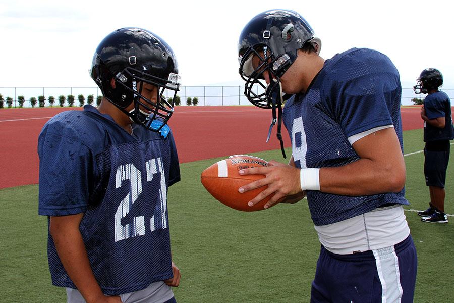 Senior quarterback Chase Newton explains a play to first-year freshman Jarin Correa. With no jv football team this year, there is a large number of underclassmen on the singular varsity team, so many upperclassmen are helping to bring them up to a varsity level of play.