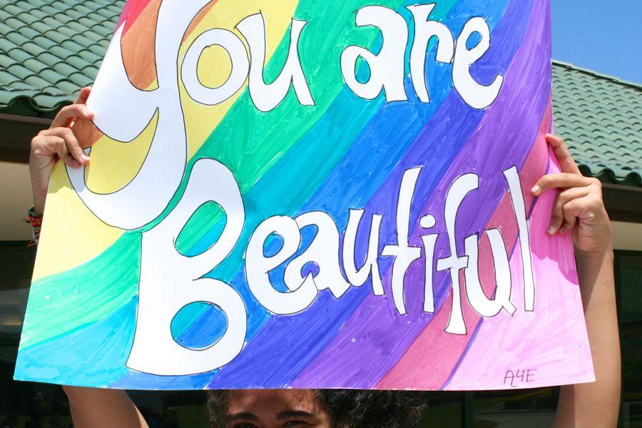 President Joelene Kuaana of Allies for Equality holds up a You are Beautiful sign on Club Sign-Up Day, August 27.