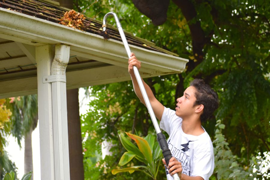 Senior Anson Souza cleans the gutters of the Kahoolawe exhibit before wiping down the stone walls at the Bailey House Museum on October 17, 2014, as part of a whole-school a community service project for Red Friday. On Pōʻalima ʻUlaʻula, students from all three campus broke into smaller groups to do community service and engage in cultural learning opportunities designed to celebrate Hawaiian unity. Some groups stayed on campus, while others, like Souzaʻs endorsement academy, visited community sites.