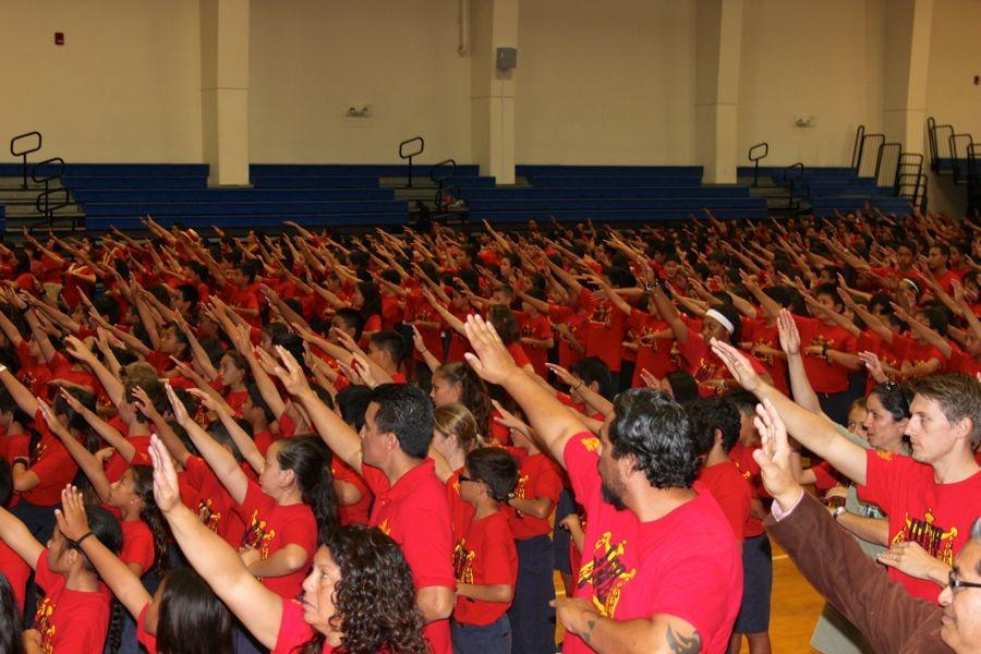 Students and teachers alike raise their arms in unison on Pōalima Ulaula.