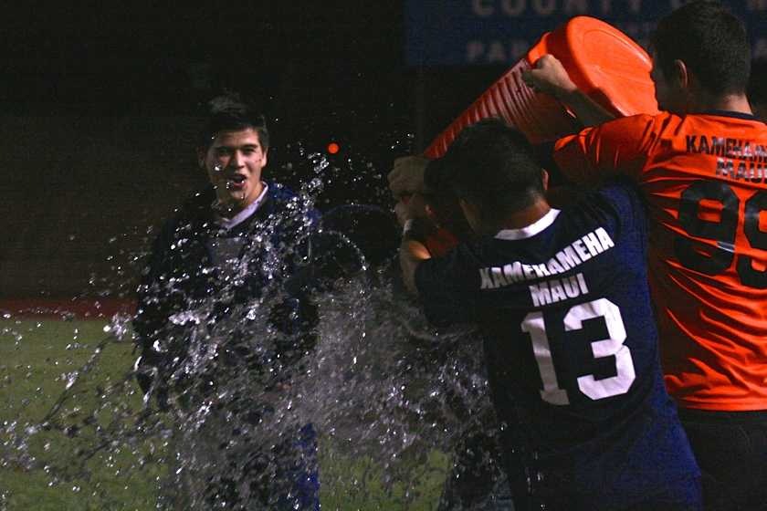 Micah Alo smiles as Daryn Nakagawa and Keola Paredes dump water on Coach Kyle Herendeen to celebrate their final win at War Memorial Stadium February 6, 2014. The Warriors defeated the Lunas and ended their season as league champions with two ties and no losses.