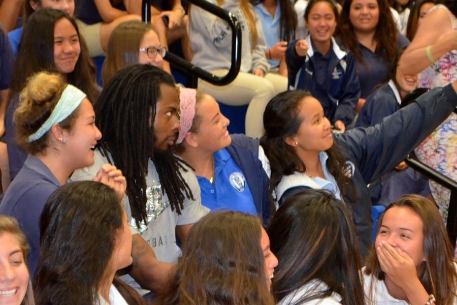 Malia Yonemura, Ayla Forsythe and Sarah Catugal take a selfie with the Seahawksʻ Richard Sherman at an assembly on Thursday, April 16. The professional football player and other Seahawks were on Maui to meet and train on the campus this week.