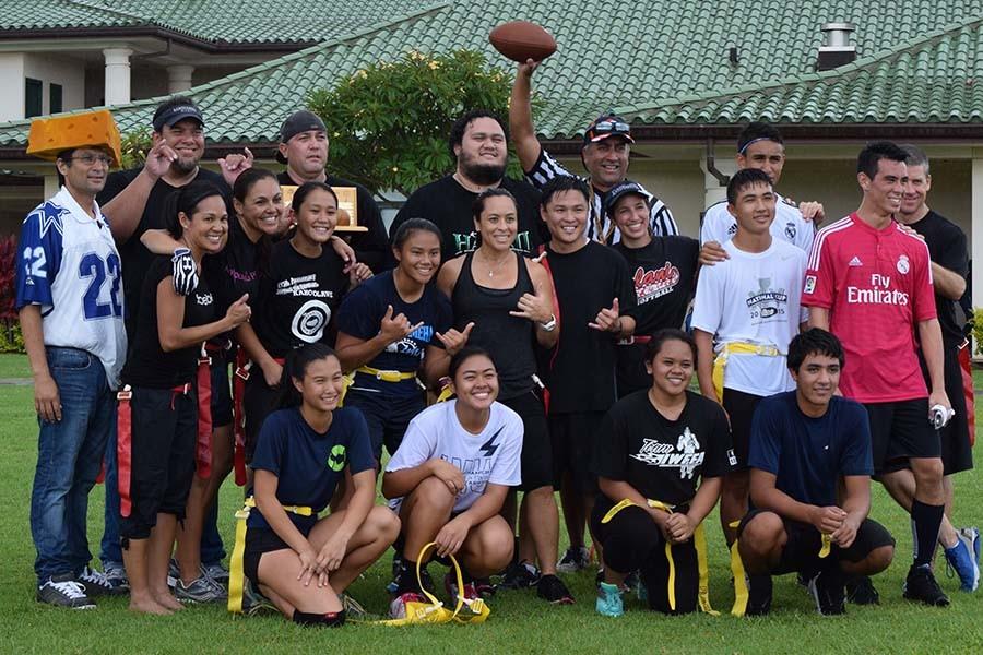 Teachers and students pose for a group photo after the traditional flag football game, the Poi Bowl, on the quad during lunch. Tuesday was known as Sports Day, and students could wear sports jerseys to represent their favorite sports teams.