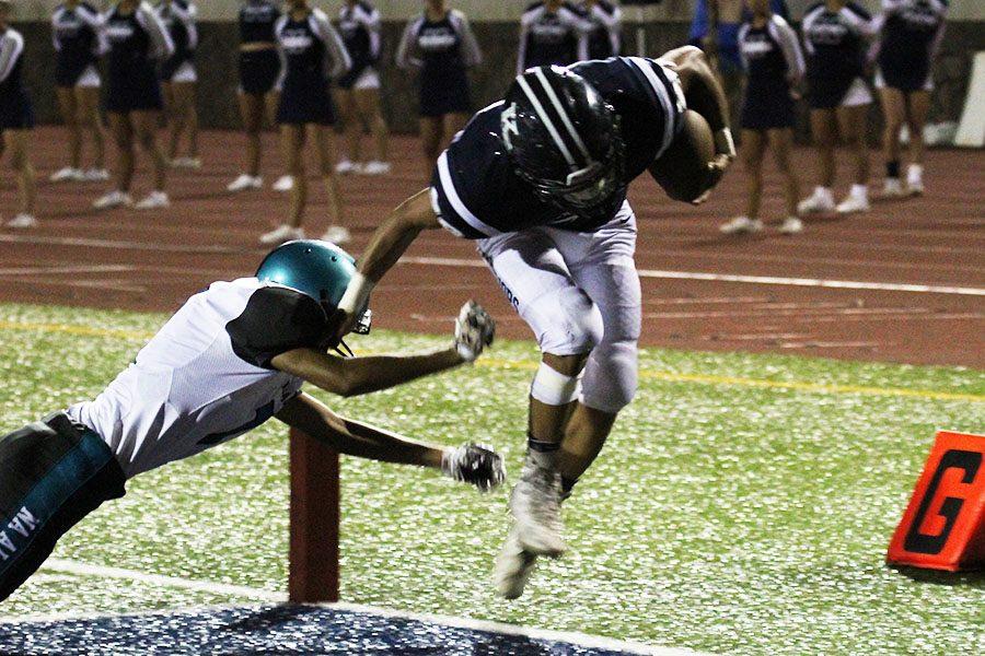 Damon Martin (#28) gallops over a Nā Aliʻi defender and into the end zone for his second rushing touchdown during the first half of the Kamehameha Maui homecoming game against King Kekaulike, Sept. 23, at Kanaiaupuni Stadium. The Warriors won 38-0.