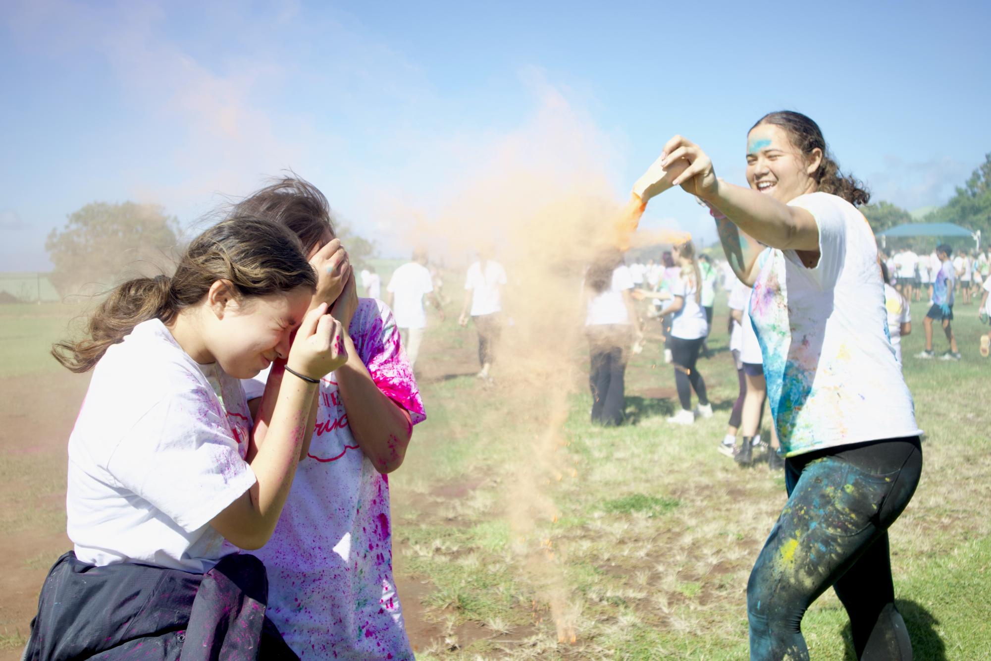 Eva "Mahea" Ane (9) showers Malia Kim (9) and Meleannah Felicilda (9) with vivid orange dye in the Color Run.